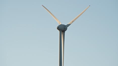 close-up of a wind turbine blade rotation in a clear blue sky, emphasizing clean energy production