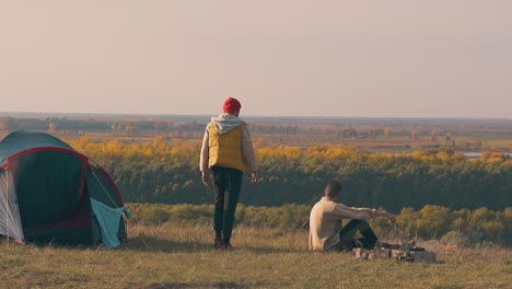 Stilvoller-Typ-Nähert-Sich-Einem-Traurigen-Freund,-Der-Am-Lagerfeuer-Sitzt