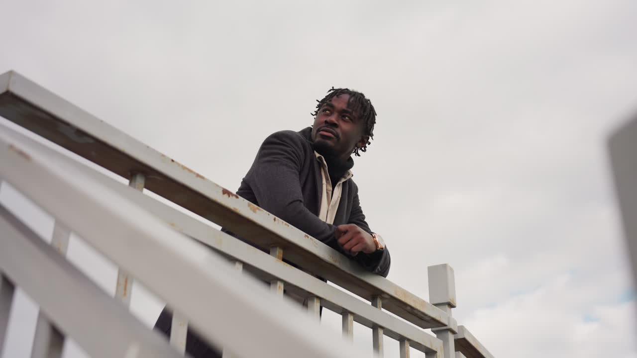 Sky and security rail display same soft color tone in outdoor scene, creating minimal balance between man-made structure and cloudy atmosphere while calm mood enhances sense of natural harmony
