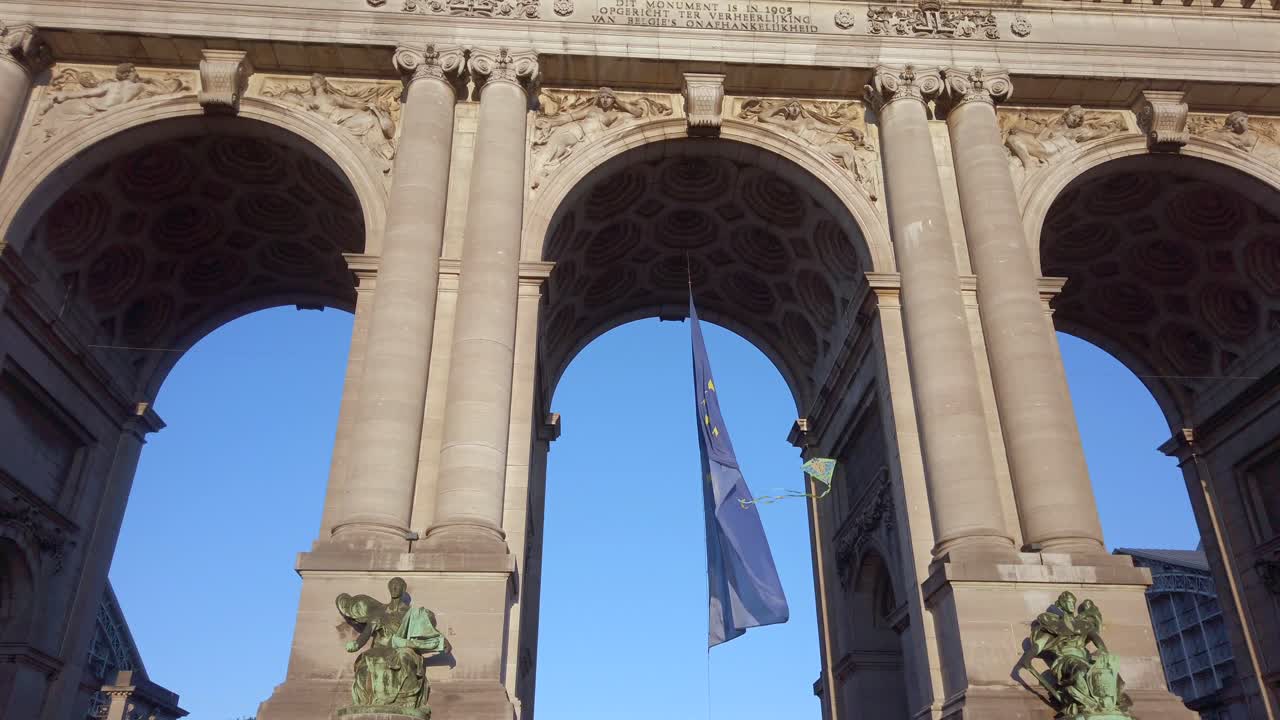 Wide view of European Union flag hanging beneath Cinquantenaire arch in Brussels