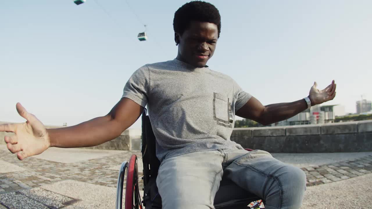 Felice uomo afroamericano che balla in sedia a rotelle all'aperto.