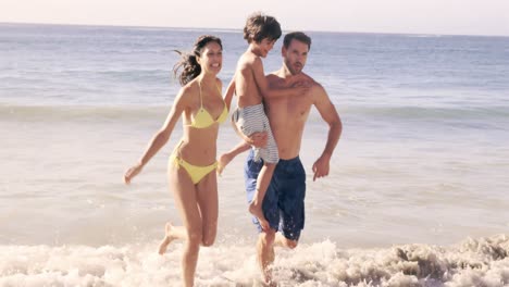 Cute-family-running-out-of-the-water-on-the-beach