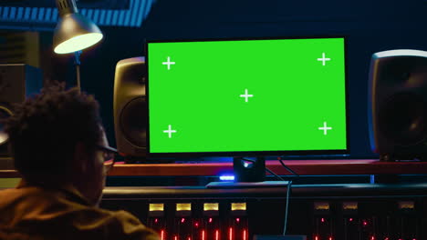 el diseñador de sonido afroamericano mira la pantalla verde para grabar y editar melodías