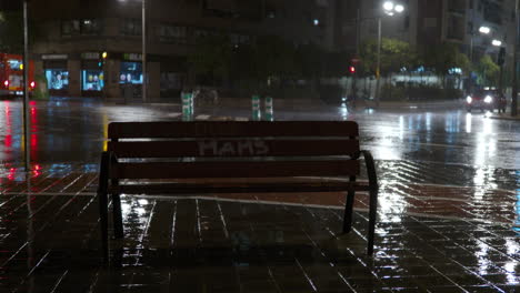 Banco-Vacío-Y-Tráfico-Por-Carretera-En-La-Ciudad-En-La-Noche-Lluviosa