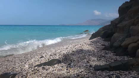 Paradiesischer-Strand,-Geschützt-Durch-Geschnitzte-Klippen-An-Der-Wunderschönen-Küste-Des-Ionischen-Meeres-Mit-Türkisfarbenem-Wasser,-Das-An-Der-Felsigen-Küste-In-Albanien-Plätschert