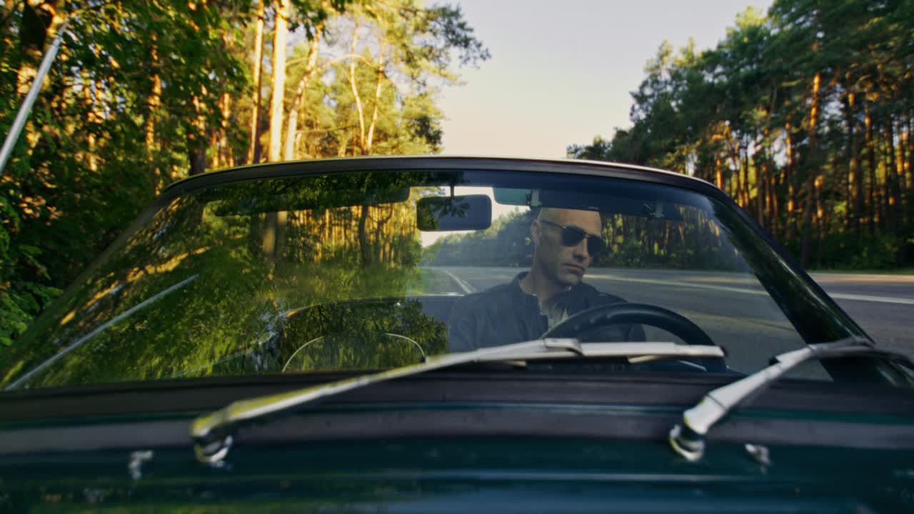 Uomo alla guida di una decappottabile durante un viaggio on the road