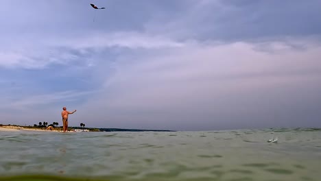vista submarina de un hombre adulto en vacaciones de verano en traje de baño en la playa jugando con cometa de juguete