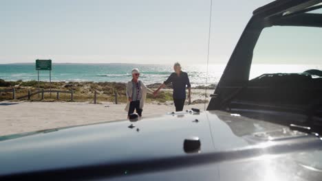 senior couple with a car at the beach