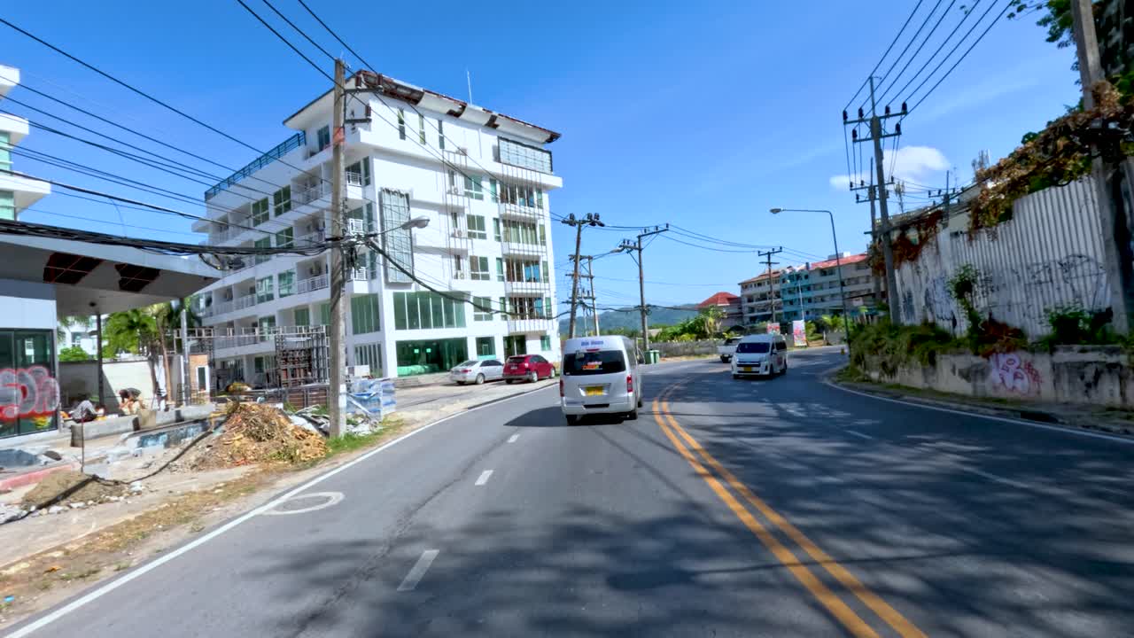 Vehicles and pedestrians move along a tropical urban street, bright daylight, smooth forward camera motion