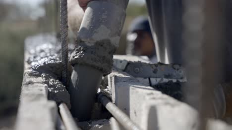 construction worker pouring wet concrete from pipe into wall formwork, close up