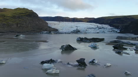 aerial drone cinematic to the right movement of solheimajokull glacier iceland lagoon and icebergs late afternoon