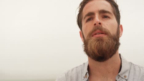 front view of caucasian man standing with arms crossed on the beach 4k