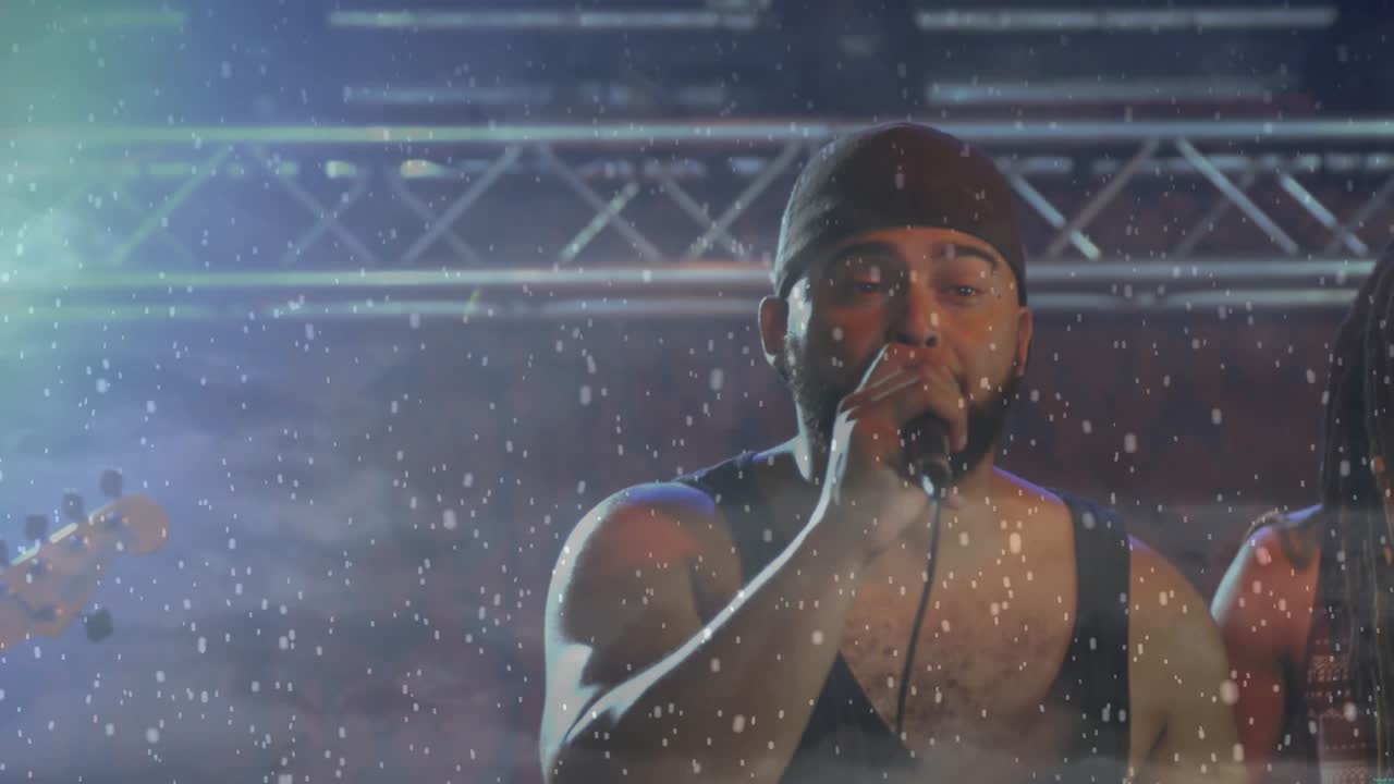 Falling snow revealing lead singer gripping mic and raising arm while concluding concert verse