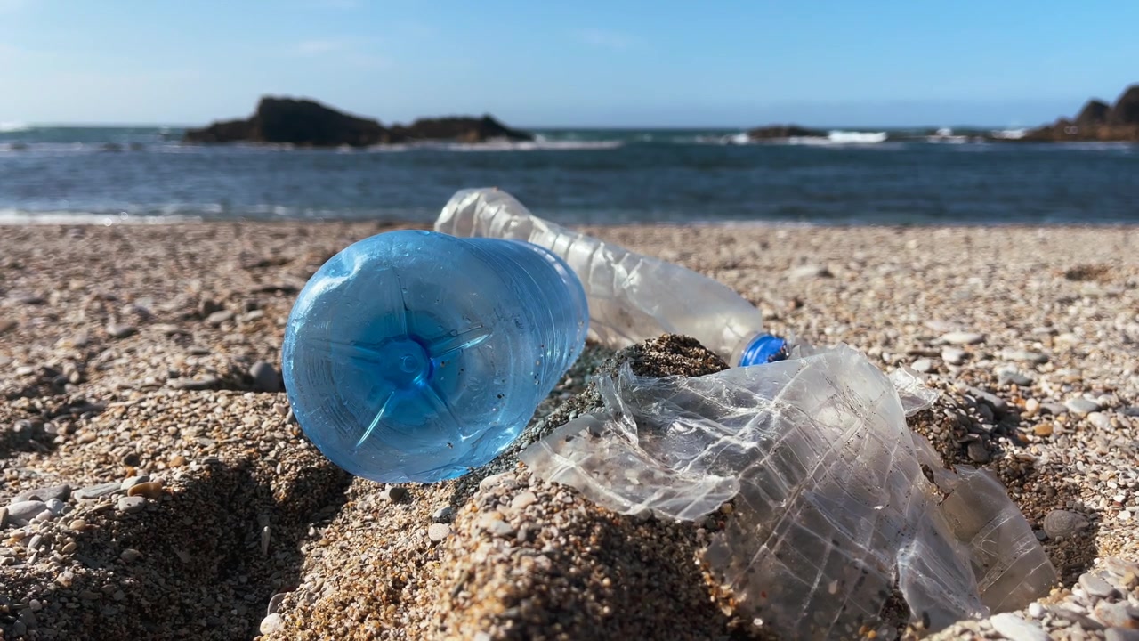 Rifiuti di plastica che inquinano una spiaggia, a rappresentare l'impatto umano sugli ecosistemi e il cambiamento climatico.