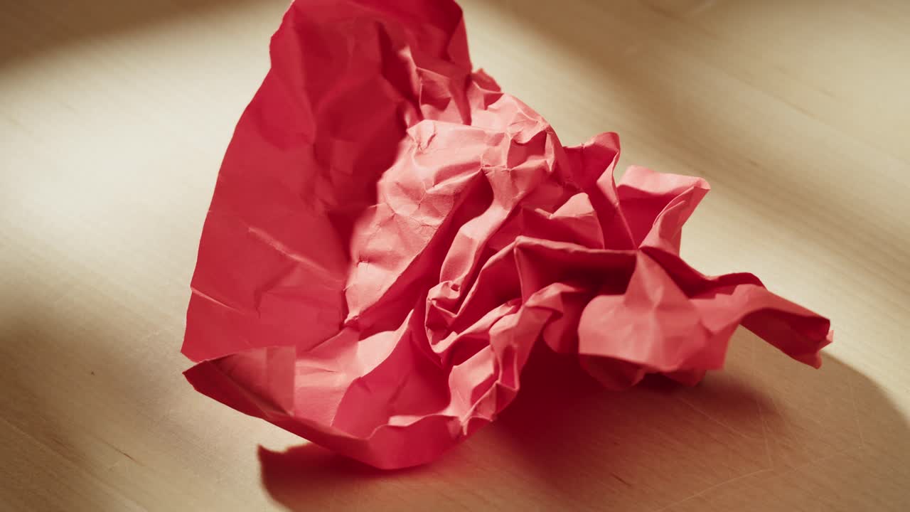 Hand crumpling red paper on wooden table
