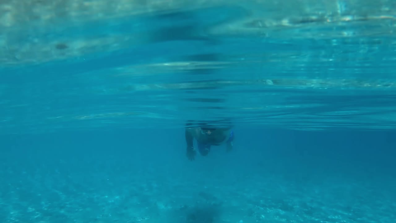 Man in swimming goggles under the water, Aegean sea. Slow motion, underwater shooting. Greece