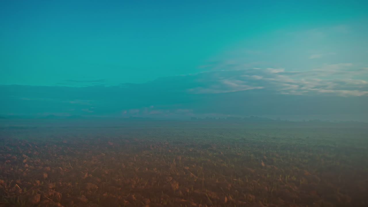 timelapse de toma amplia de una enorme llanura cubierta de hierba sobre la que pasan nubes oscuras y se forma una densa niebla