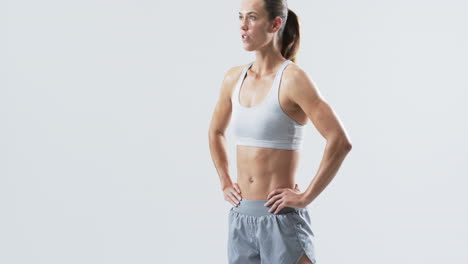 Young-Caucasian-woman-athlete-stands-confidently-in-a-studio-setting-on-a-white-background