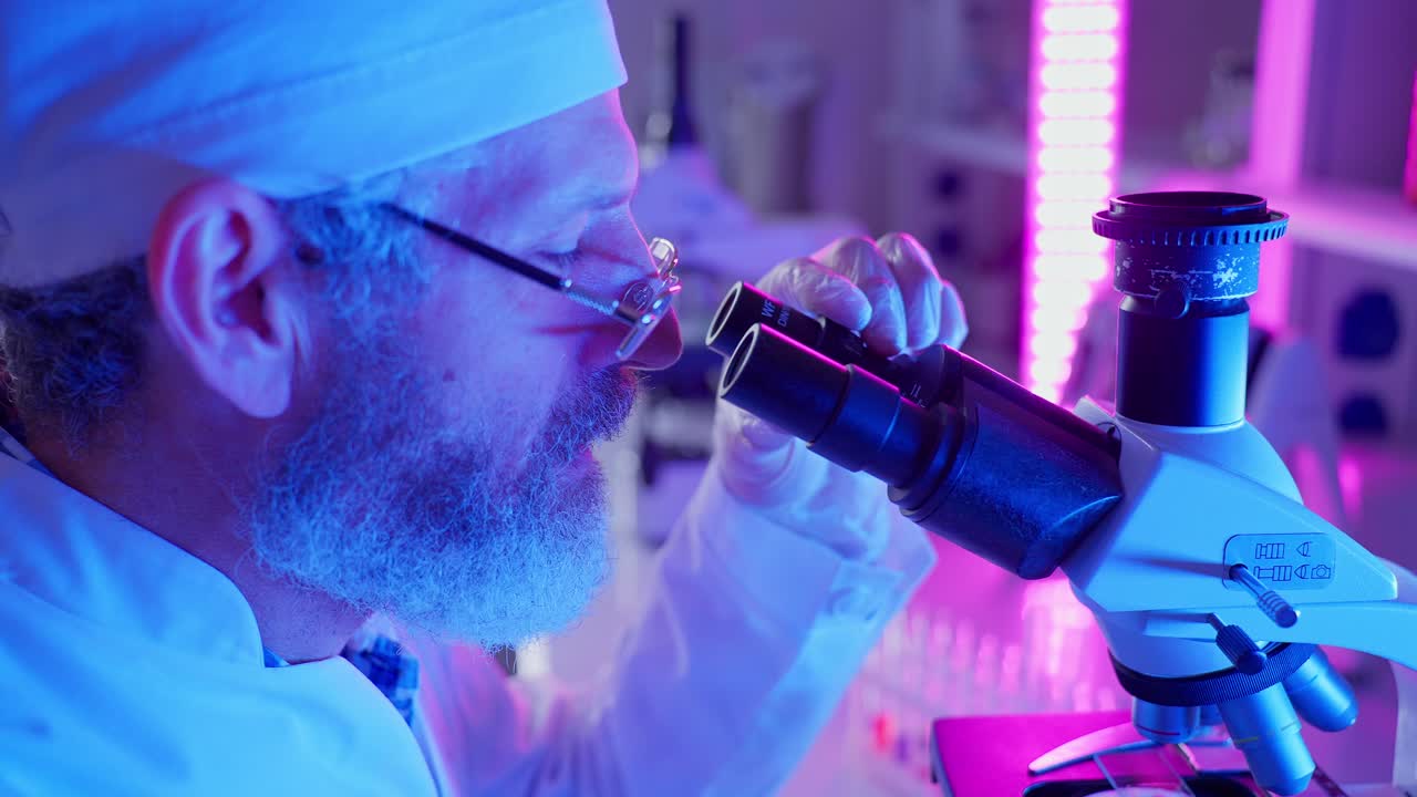 Miespuolinen tiedemies katsoo mikroskoopin läpi modernissa laboratoriossa