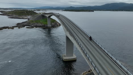 atlantic road bridge with bike rider and traffic passing, norway