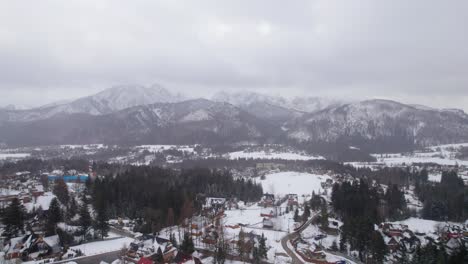 drone lifting shot of the high mountains near zakopane in poland while snow is falling