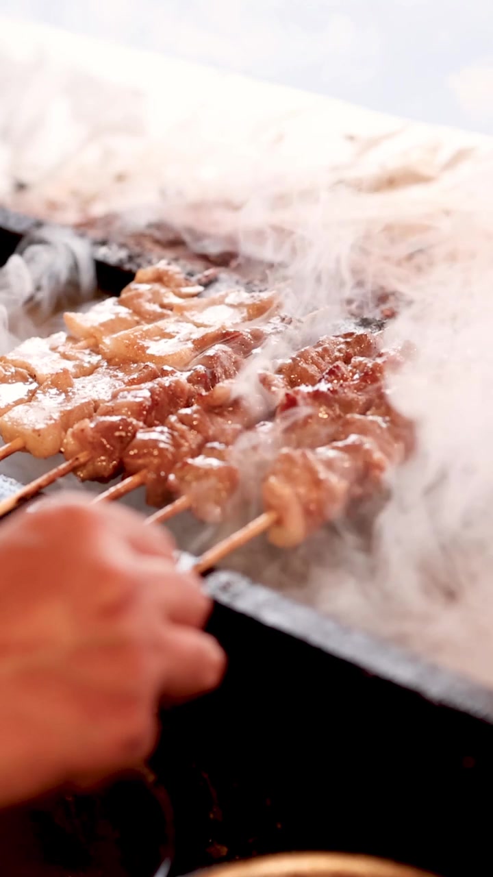 Cottura di spiedini di carne su una griglia fumante