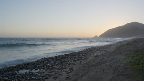 Vista-A-Nivel-De-Playa-De-Las-Olas-Rodando-Hacia-La-Playa-De-Mondo-Al-Atardecer-Ubicada-En-El-Sur-De-California