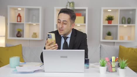 Hombre-Trabajador-De-Oficina-En-Casa-Hablando-Por-Teléfono-Facetime-Felizmente.