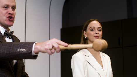 hombre en traje elegante con martillo y mujer sosteniendo un libro