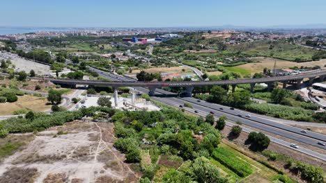drone disparado volando sobre algunos campos y sobre una autopista y un puente de tren