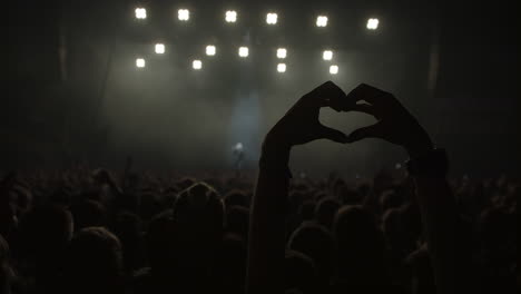 person showing a heart with hands on a live concert