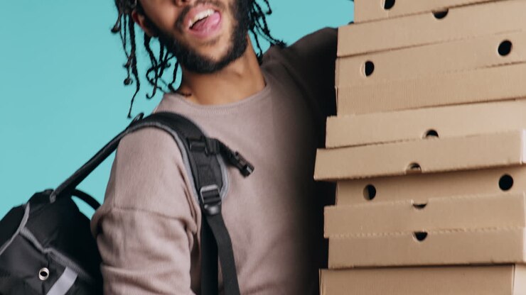 Ritratto di fattorino di pizza sorridente che tiene in mano ordini da asporto, su sfondo blu.