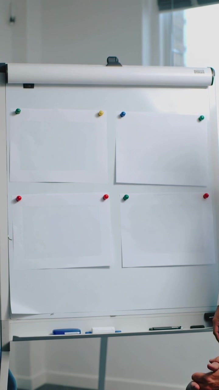 Video verticale: Donna in top che si protende indicando un grafico con spilli colorati mentre conduce una riunione, con spazio per il testo.