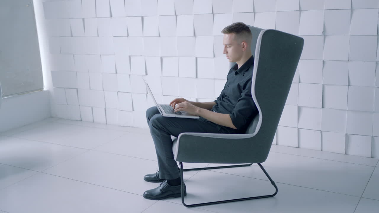 현대 의자 에서 노트북 을 사용 하는 사람