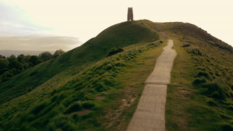 a drone shot flying along a foot path up glastonbury tor, a hill in somerset uk