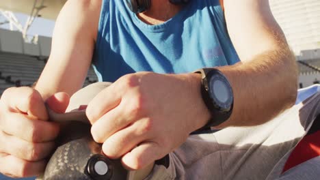 midsection of caucasian disabled male athlete sitting, putting on running blade