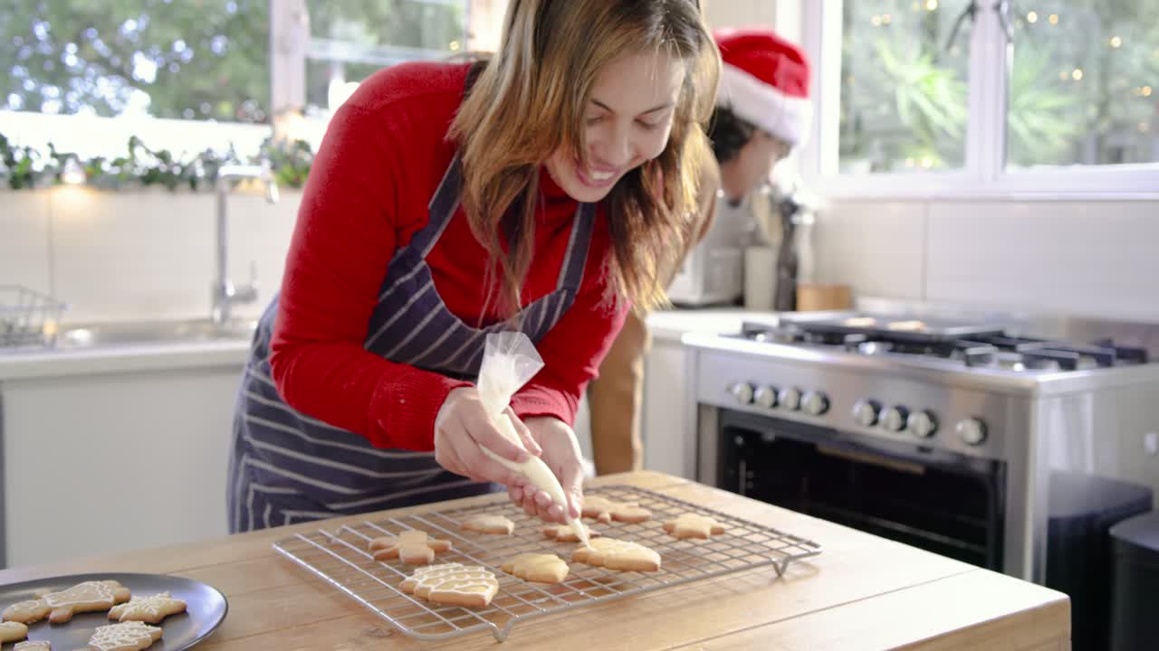 Pressing icing bag on countertop, woman is decorating tree cookie for holiday baking tasks