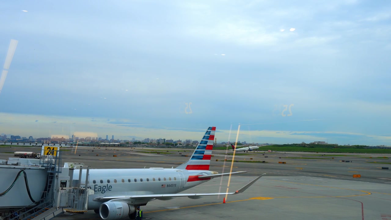 Chicago, AS, 27 Mei 2026: Pesawat jet American Eagle di gerbang dekat landasan pacu. Pesawat regional di jembatan garbarata menghadap jalur taksi, peralatan layanan, dan pesawat-pesawat di kejauhan di balik kaca terminal.