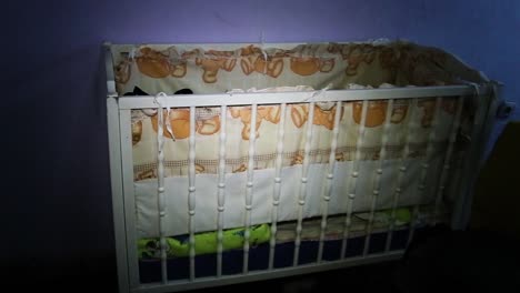 an empty baby crib with patterned bedding in a room.
