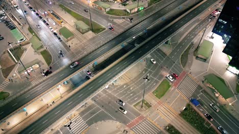 Aerial-car-traffic-and-people-crossing-road-at-night-in-Warsaw-city-downtown