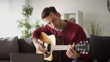 video de un hombre tocando la guitarra acústica en casa
