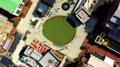 Aerial-drone-shot-looking-straight-down-and-spinning-slowly-over-the-green-turf-and-retail-stores-at-Atlantic-Station-in-Atlanta,-Georgia