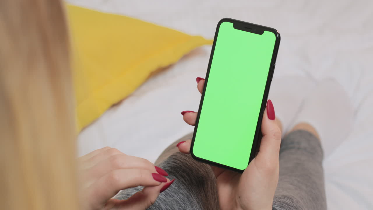 mujer sosteniendo un teléfono inteligente con pantalla verde