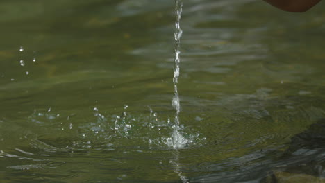 toma en cámara lenta de una mujer sacando agua con la mano en agua de manantial tranquila