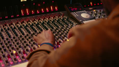 audio technician producing new music at mixing console in control room