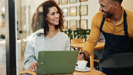 woman working on laptop in cafe with waiter