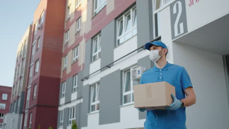 an young mailman courier with a protective mask and gloves is delivering a parcel directly to a customer home with safety. concept of courier home delivery e-commerce shipping virus covid