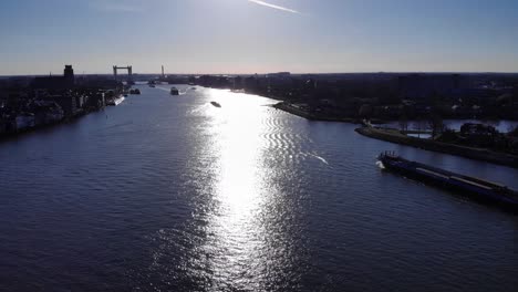 cargo vessels sailing over the river oude maas with at the background the white railway lift bridge of the city dodrecht on a bright calm winter day