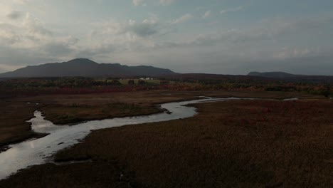 Cours-D&#39;eau-Shonyo-Strom-Durch-Die-Wiesen-Mit-Berglandschaft-Im-Hintergrund-Unter-Bewölktem-Himmel-In-Magog,-östliche-Townships,-Quebec-Kanada