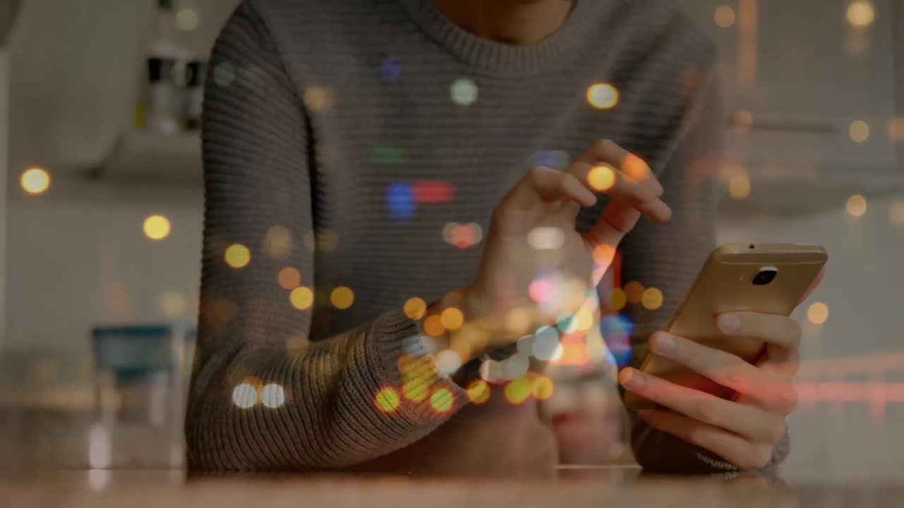 manchas de luces bokeh contra un hombre caucásico que usa un teléfono inteligente en casa